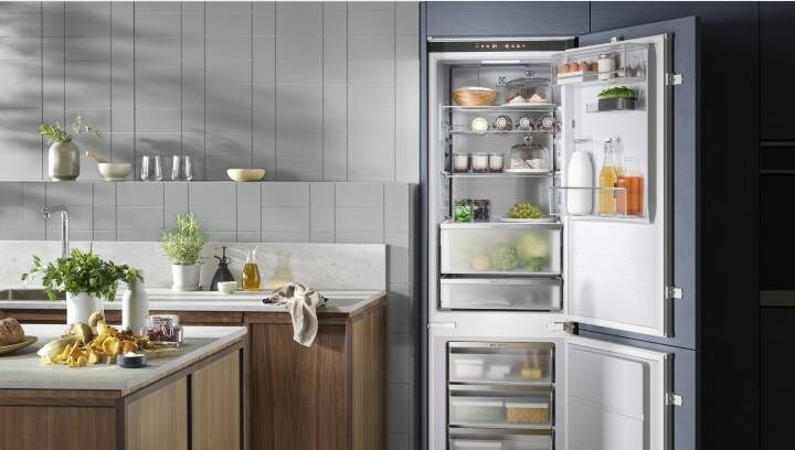 An open fridge freezer filled with fresh food stored in convenient compartments