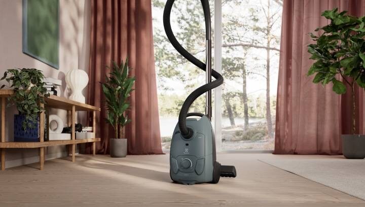 The latest corded vacuum cleaner placed in the living room with green plants in the background